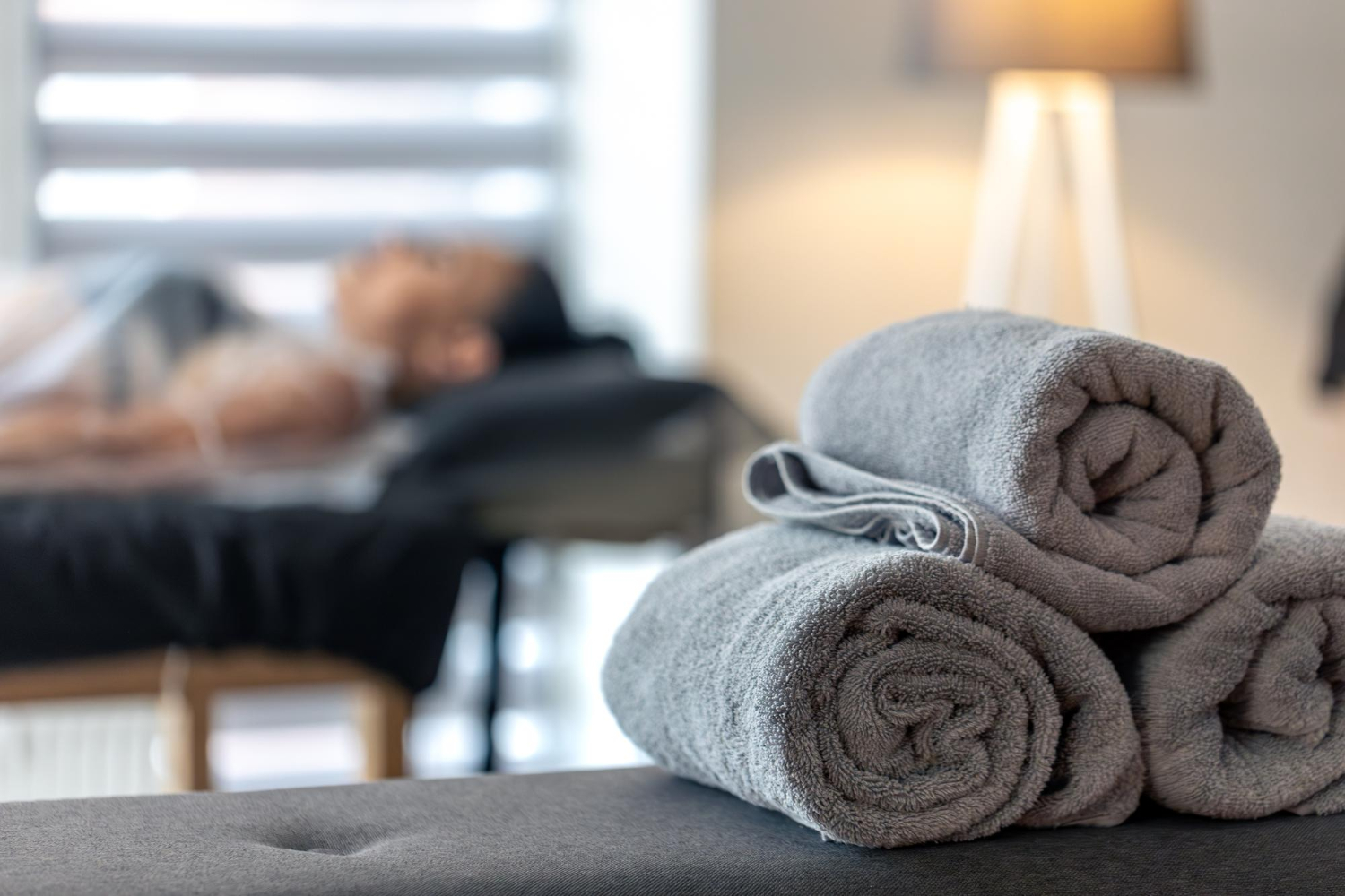 Serviettes de spa grises avec un client à proximité, lumière chaude et atmosphère de détente